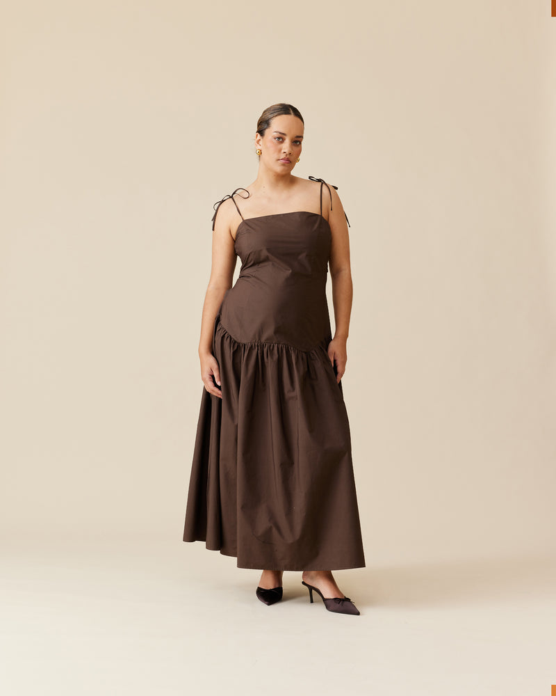 TRULLI MAXI DRESS JAVA | Cotton maxi dress that is fitted through the body, then falls to a floaty basque style mini skirt. This dress features a dropped bodice-style waistline with a full skirt, and...