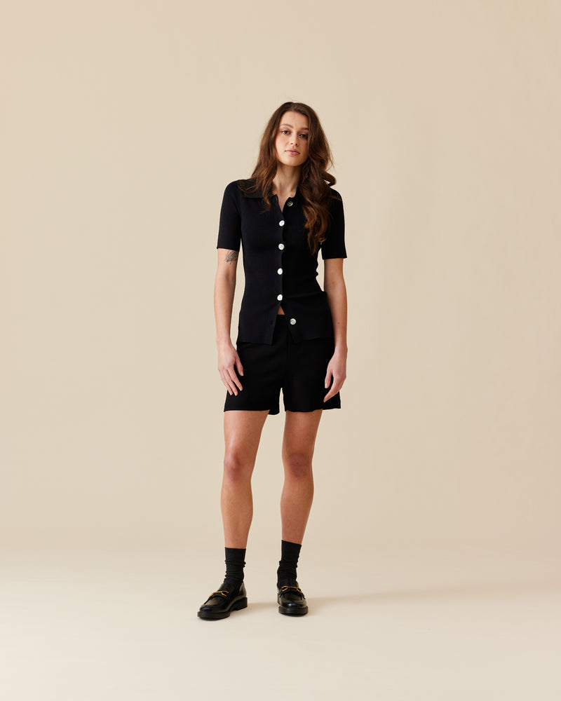 LOTTIE SHORT SLEEVE CARDIGAN BLACK | Collared short sleeve cardigan designed in a light-weight black knit. This piece features oversized shell buttons down the centre, that can be style buttoned-up or worn open as a layering...