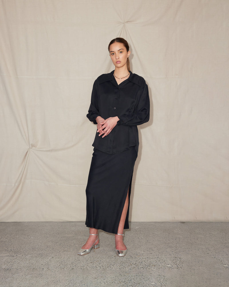 JOHARI SHIRT BLACK | Oversized drop shoulder shirt with long sleeves. With an exaggerated collar and sleeve cuffs that button into tucks, cut from a lustrous black cupro. This Johari shirt has been sewn...