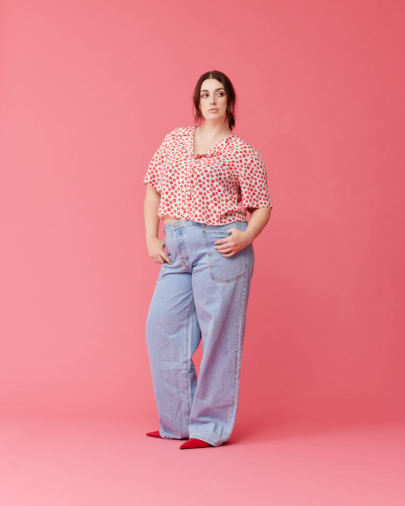 KAARINA SILK SHIRT RED DAISY | Short sleeve silk shirt with ruffles down the placket and a rounded collar. Designed in our RUBY red daisy print, this shirt can be styled as a layering piece or...