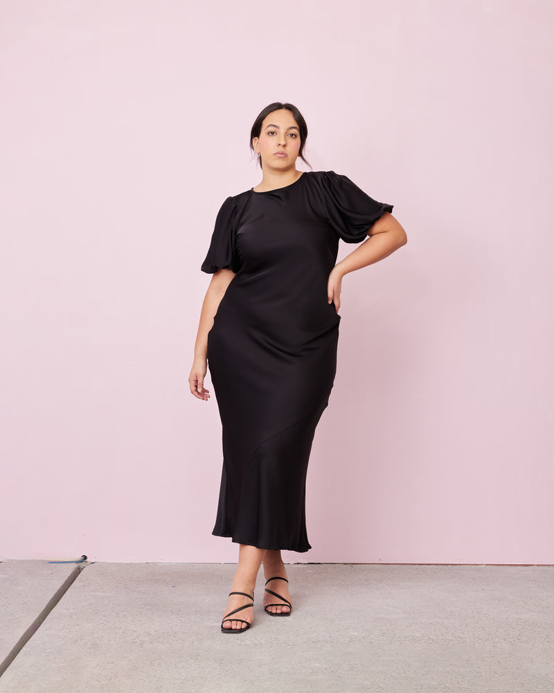 KENDALL SATIN DRESS BLACK | Bias cut satin midi dress with puff sleeves and a keyhole button closure at the back neck. The bias silhouette of this dress gently contours the body, while the satin...