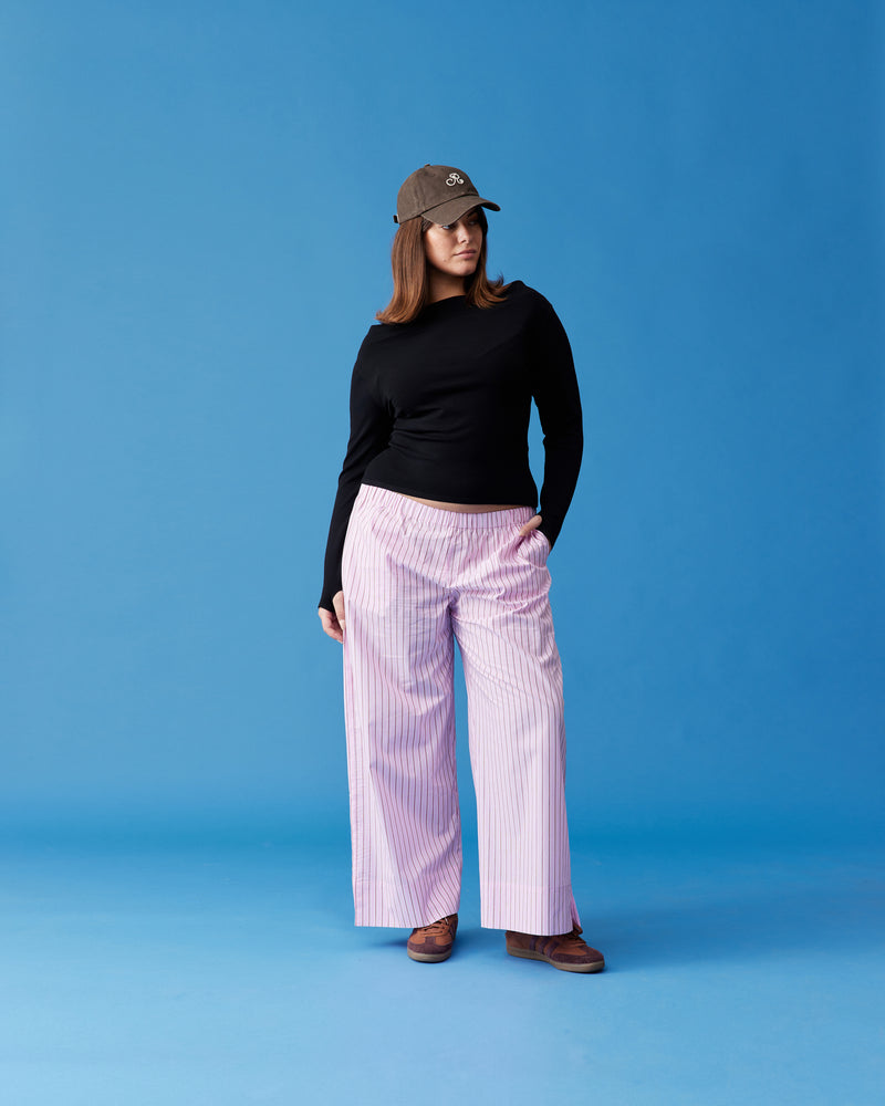 CASH PANT PINK RED STRIPE | Straight leg cotton pant with an elastic waistband, designed in pink and red striped cotton. These pants sit relaxed and wide and have side and back pockets. A trans seasonal...