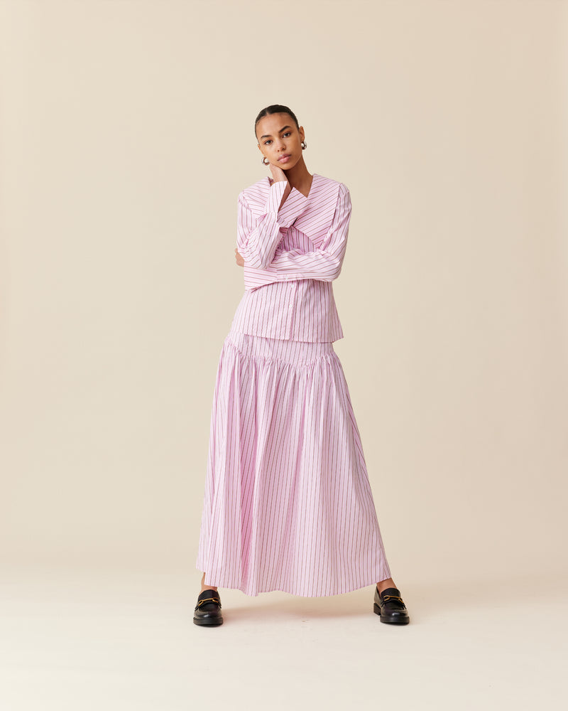 TRULLI SKIRT PINK RED STRIPE | Floaty basque style maxi skirt imagined in a pink striped cotton. This skirt features an asymmetrical bodice-style waistline, that falls to a full, wide skirt.
