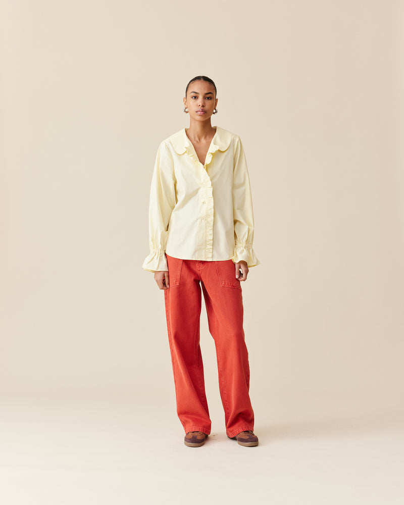 SANDLER RUFFLE SHIRT BUTTER | Long sleeve butter yellow shirt with ruffles down the placket and a rounded collar. This top features elasticated ruffle cuffs, this piece is an elevated take on the classic shirt...