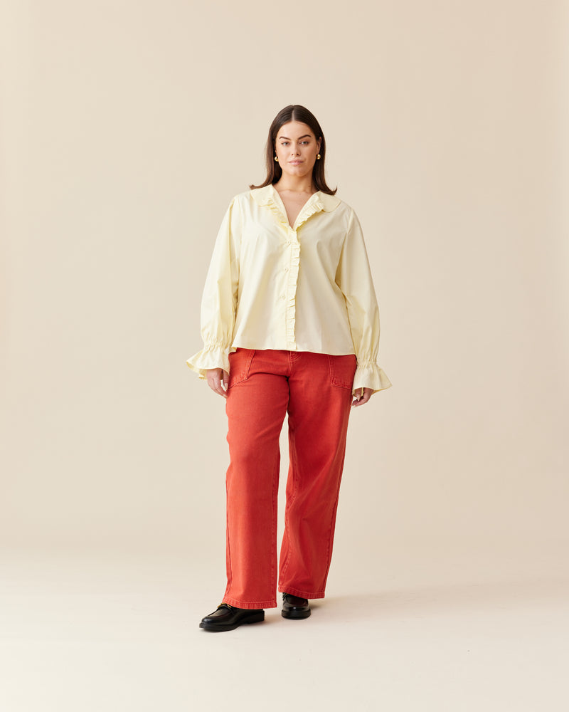 SANDLER RUFFLE SHIRT BUTTER | Long sleeve butter yellow shirt with ruffles down the placket and a rounded collar. This top features elasticated ruffle cuffs, this piece is an elevated take on the classic shirt...