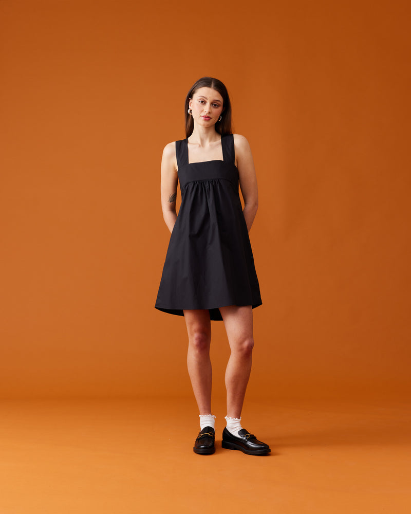 MARGIE TIE MINI DRESS BLACK | Cotton mini dress with a square band bust. The skirt falls into an A-line shape with an exposed back and bow tie closure.
