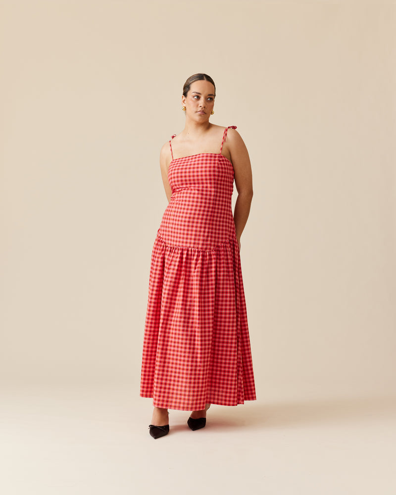 TRULLI MAXI DRESS RED TARTAN | Cotton tartan maxi dress that is fitted through the body then falls to a floaty basque style skirt. This dress features a dropped bodice-style waistline with a full skirt and...