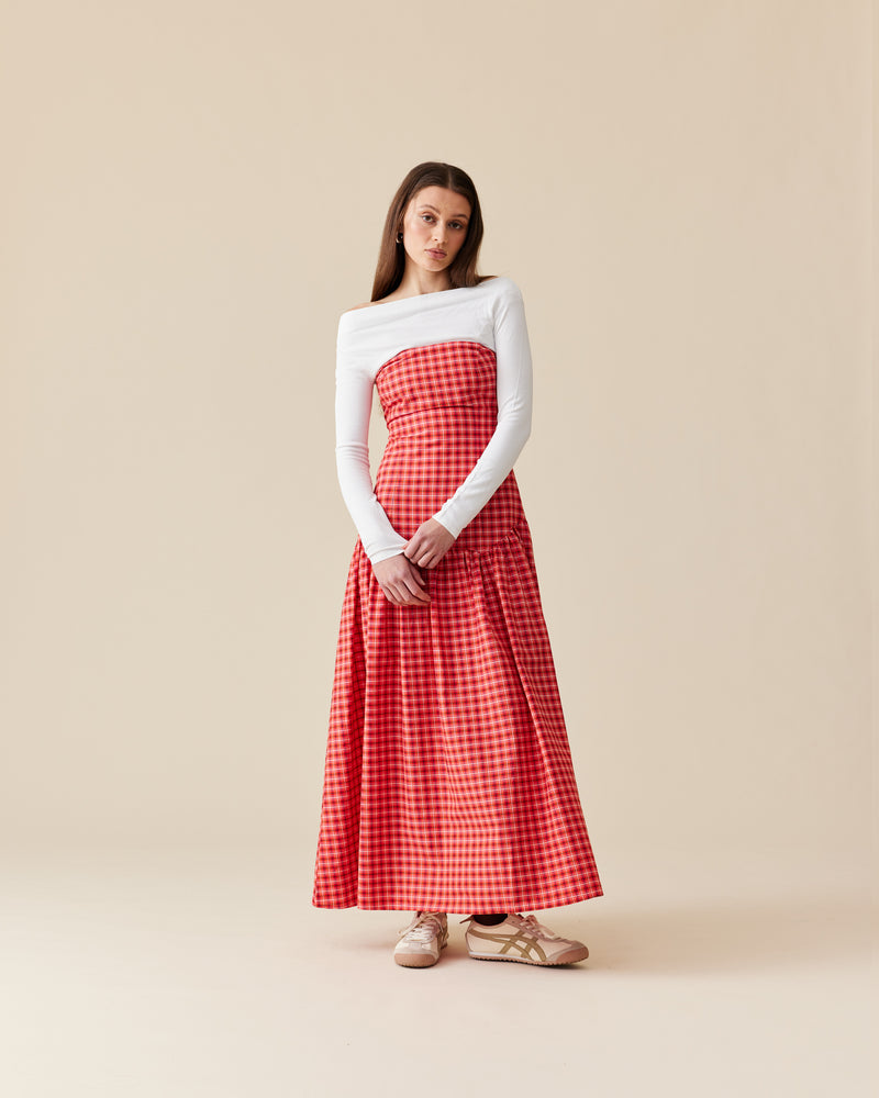 TRULLI MAXI DRESS RED TARTAN | Cotton tartan maxi dress that is fitted through the body then falls to a floaty basque style skirt. This dress features a dropped bodice-style waistline with a full skirt and...