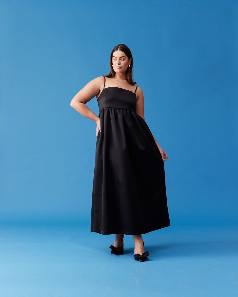 CHER MAXI DRESS BLACK | A-line maxi dress designed in a luxe heavy-weight satin. This dress has a square banded bust with darts for shaping, and falls to a softly gathered skirt with pockets. Simple...