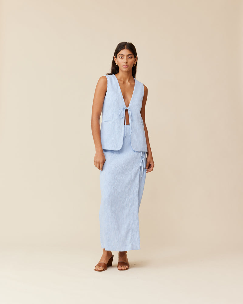 LOU TIE SKIRT PASTEL BLUE | Wrap midi skirt designed in a textured pastel blue fabric. This staple skirt is elevated by the 3 ties at the side of the skirt.