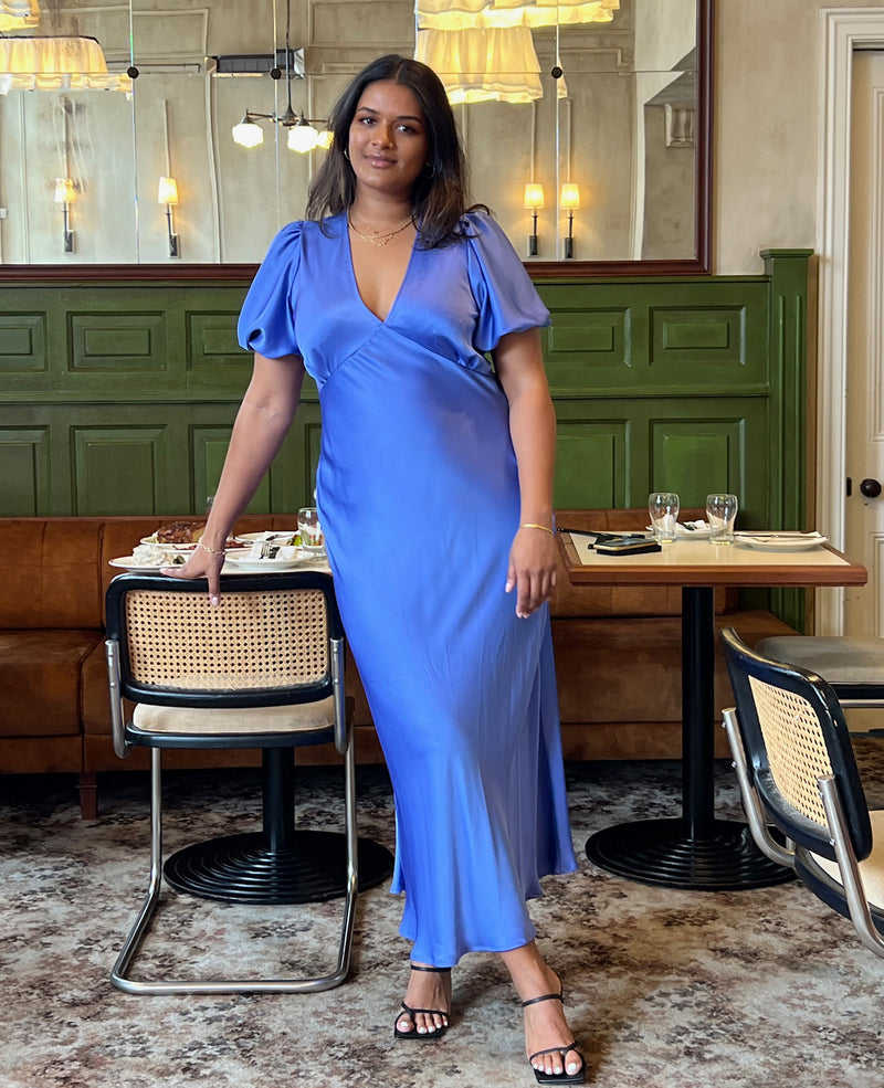 UMA SATIN DRESS PERIWINKLE | Bias cut satin maxi dress with tie closure and a V-neck front and back. Our much loved Uma Dress is back in a periwinkle satin, with elasticated puff sleeves and...